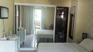 Une chambre d’hôtel comprenant un lit, un bureau avec un ordinateur, un miroir et une armoire.