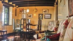 A cozy room with a fireplace, floral-patterned furniture, and framed pictures on the walls. - Castle Forest Lodge (Kimunye)
