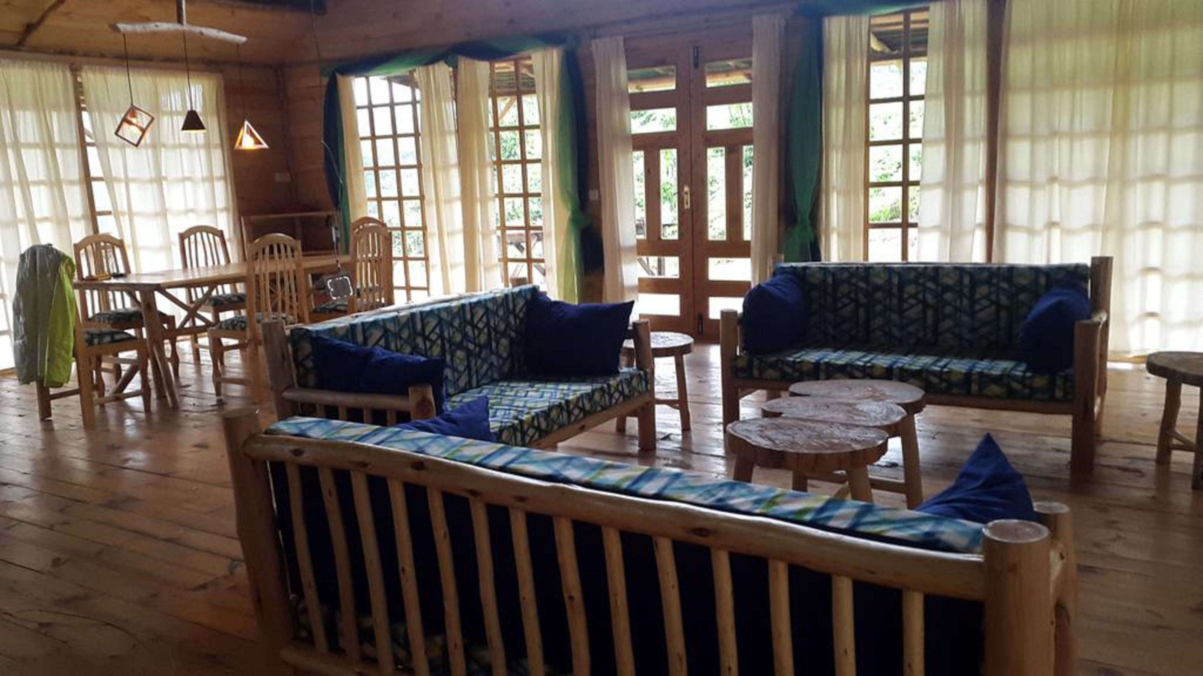 A wooden interior with a sofa, chairs, a dining table, and a small round table.