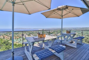 A deck with a table and benches, overlooking a scenic landscape.