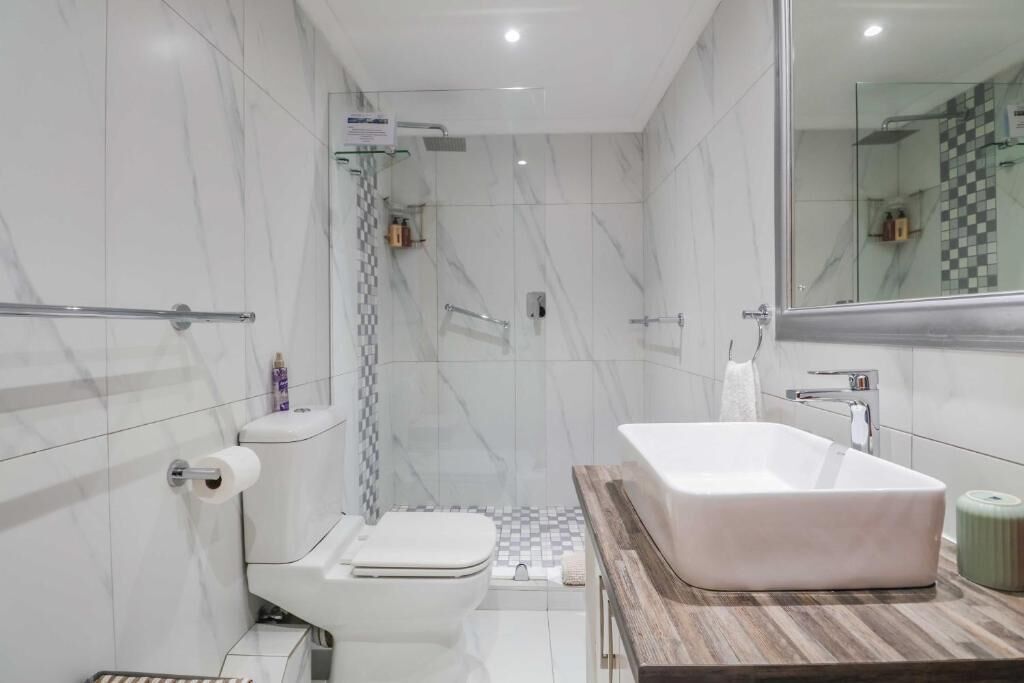 A modern bathroom with a white toilet, a freestanding bathtub, and a shower area.