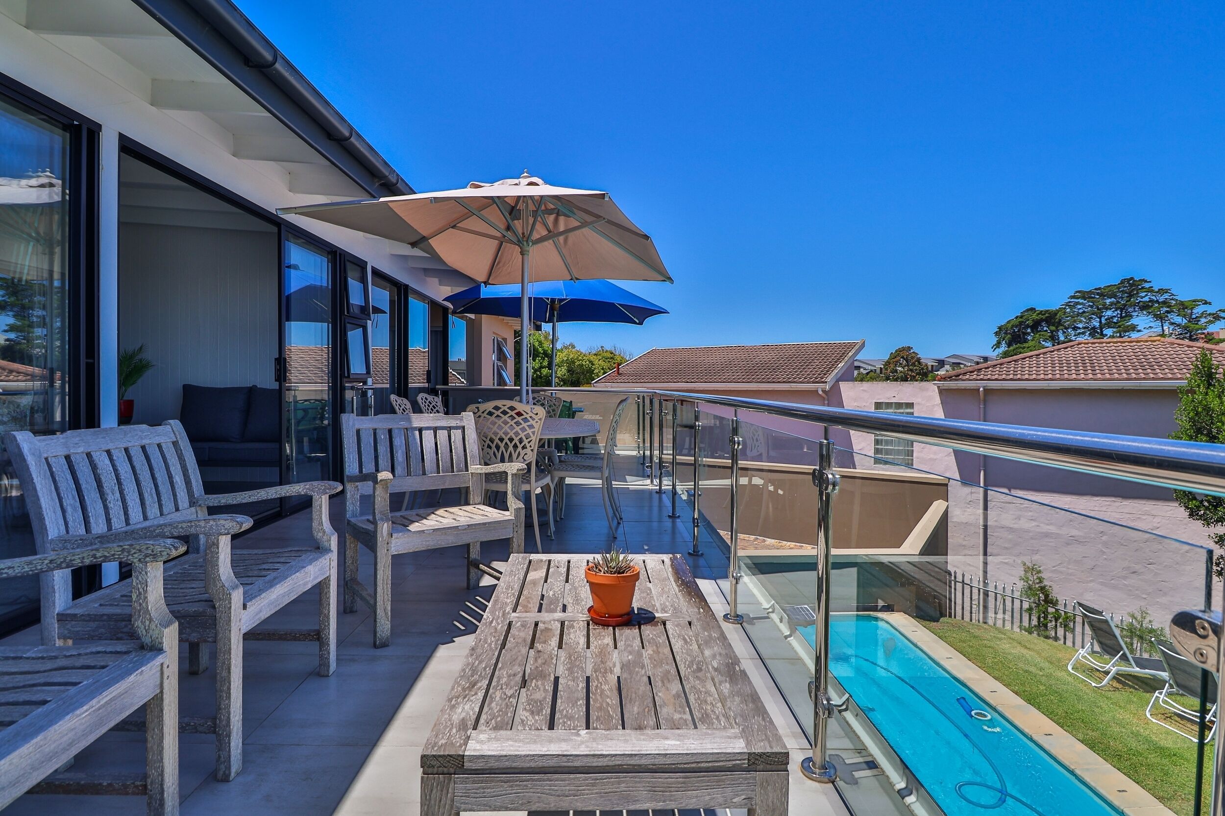A balcony with wooden furniture, a potted plant, and a pool.