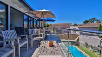 A balcony with wooden furniture, a potted plant, and a pool.