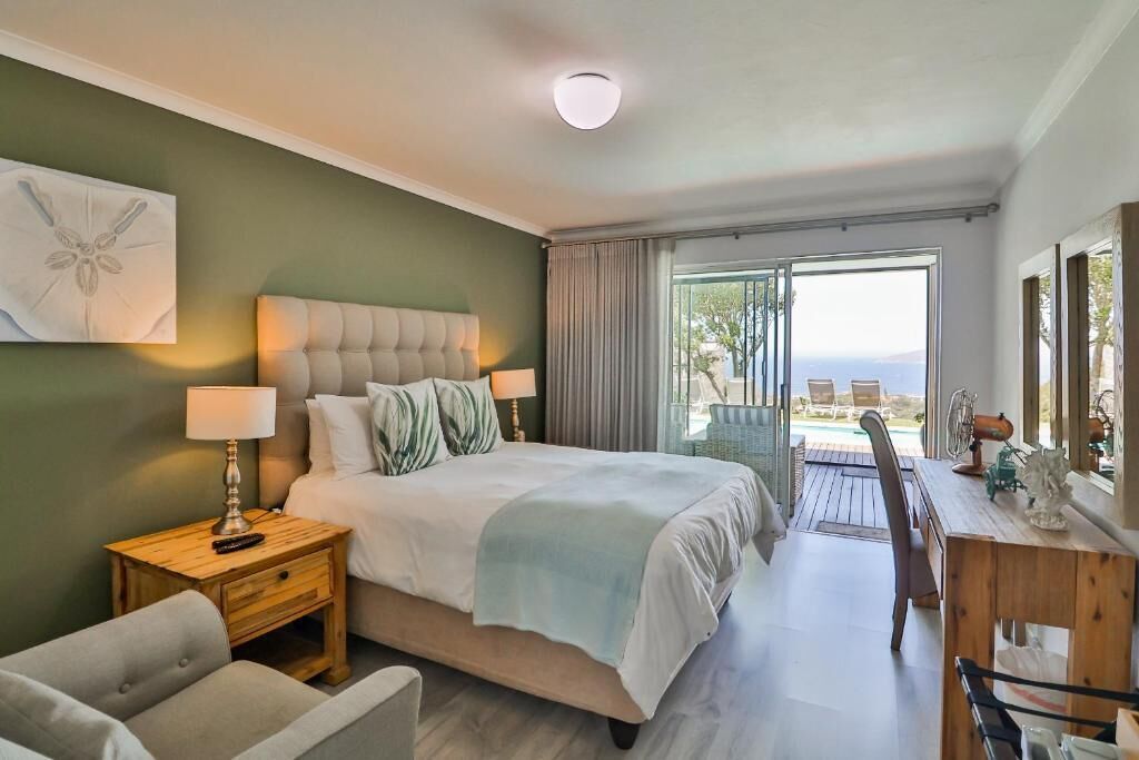 Un dormitorio con cama, mesitas de noche, un escritorio y vistas al exterior.