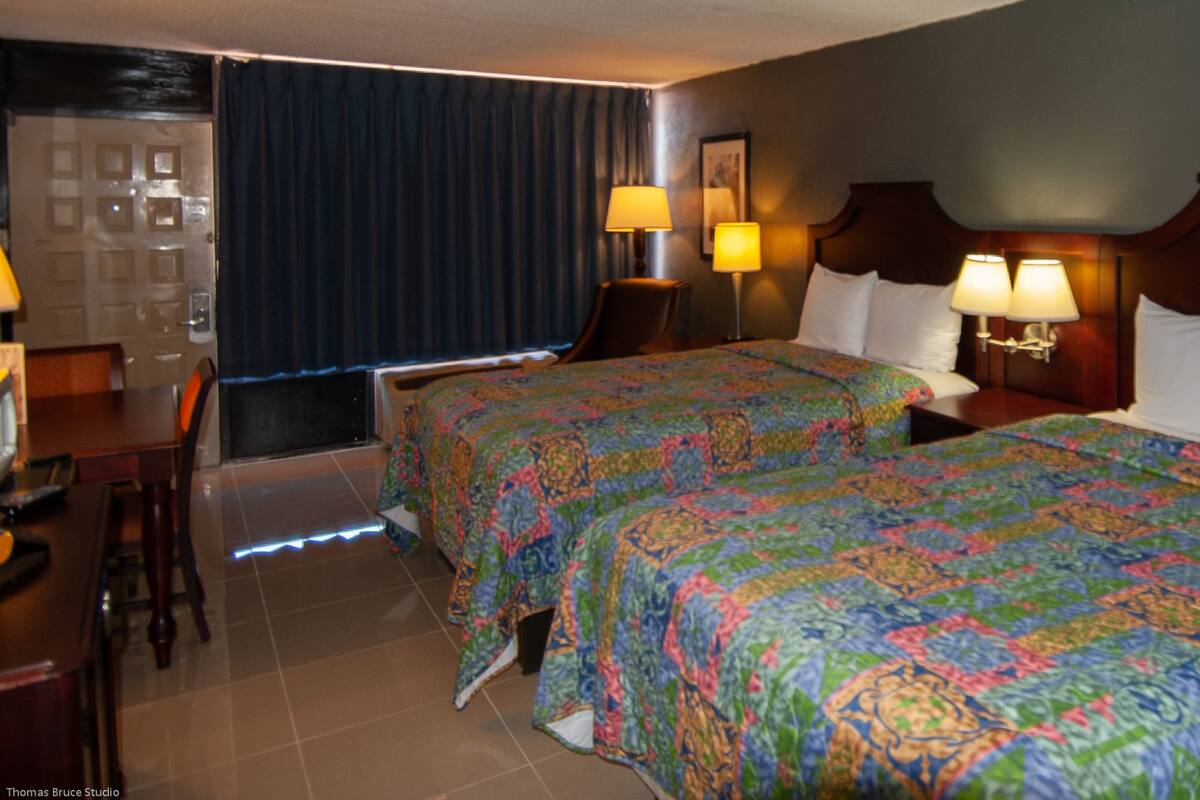 A hotel room with two beds, a desk, and a chair.