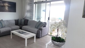 Un salon moderne avec un canapé gris, une table basse blanche et une plante orchidée en pot.