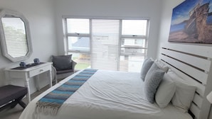 Une chambre à coucher avec un lit, un bureau, une chaise et une fenêtre avec des stores.