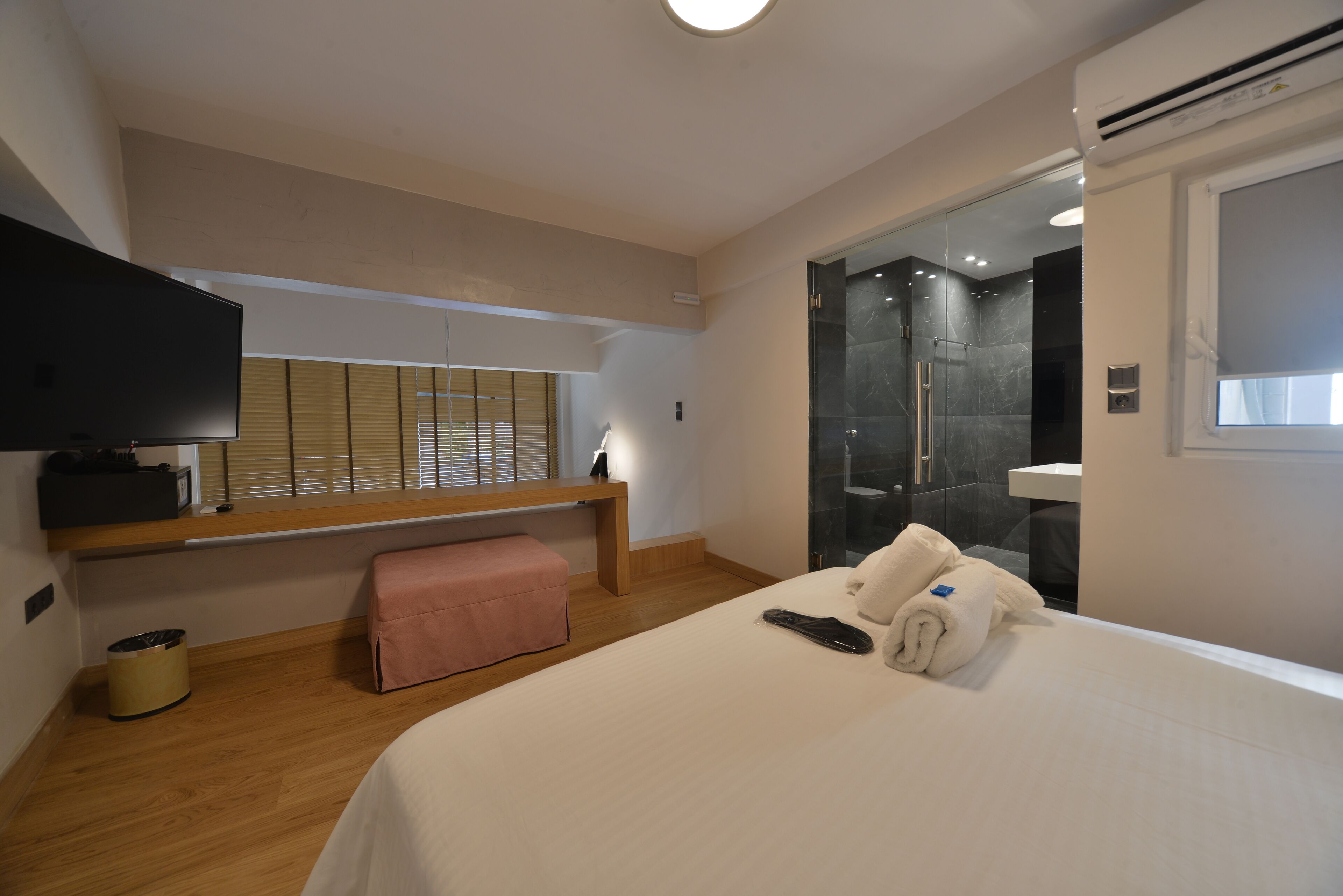 Ein Hotelzimmer mit Bett, Fernseher, Sitzbank, Dusche und Fenster.