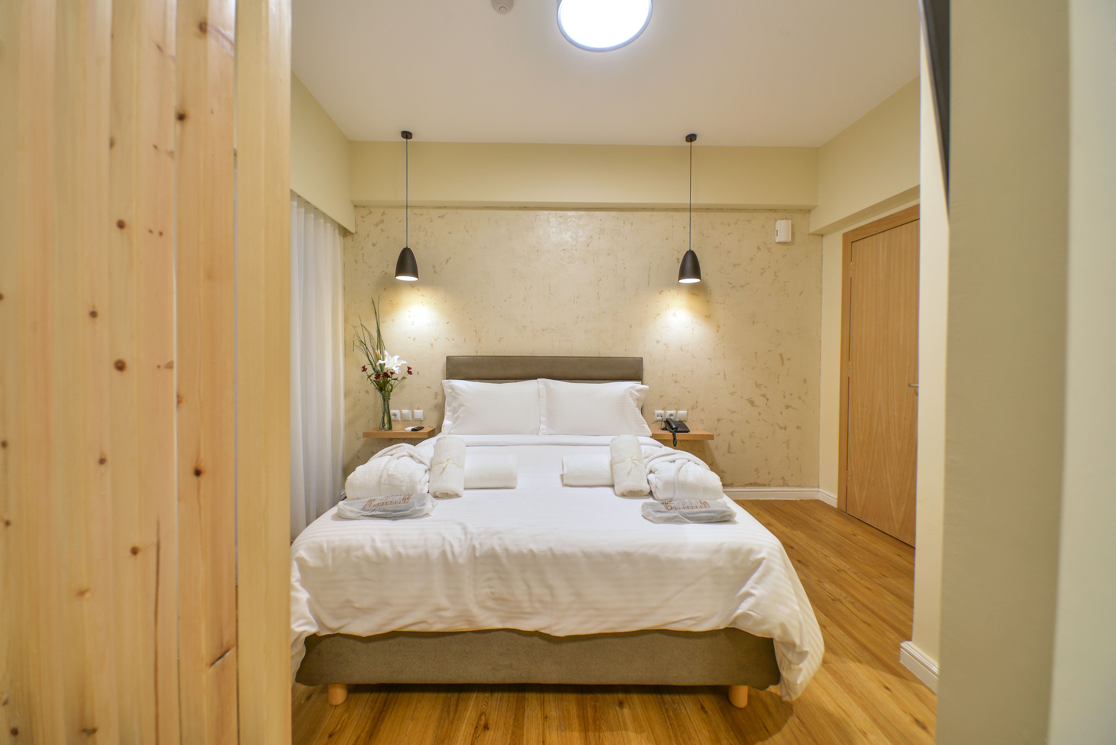Un letto rifatto con lenzuola bianche, due comodini con lampade e un pavimento in legno.