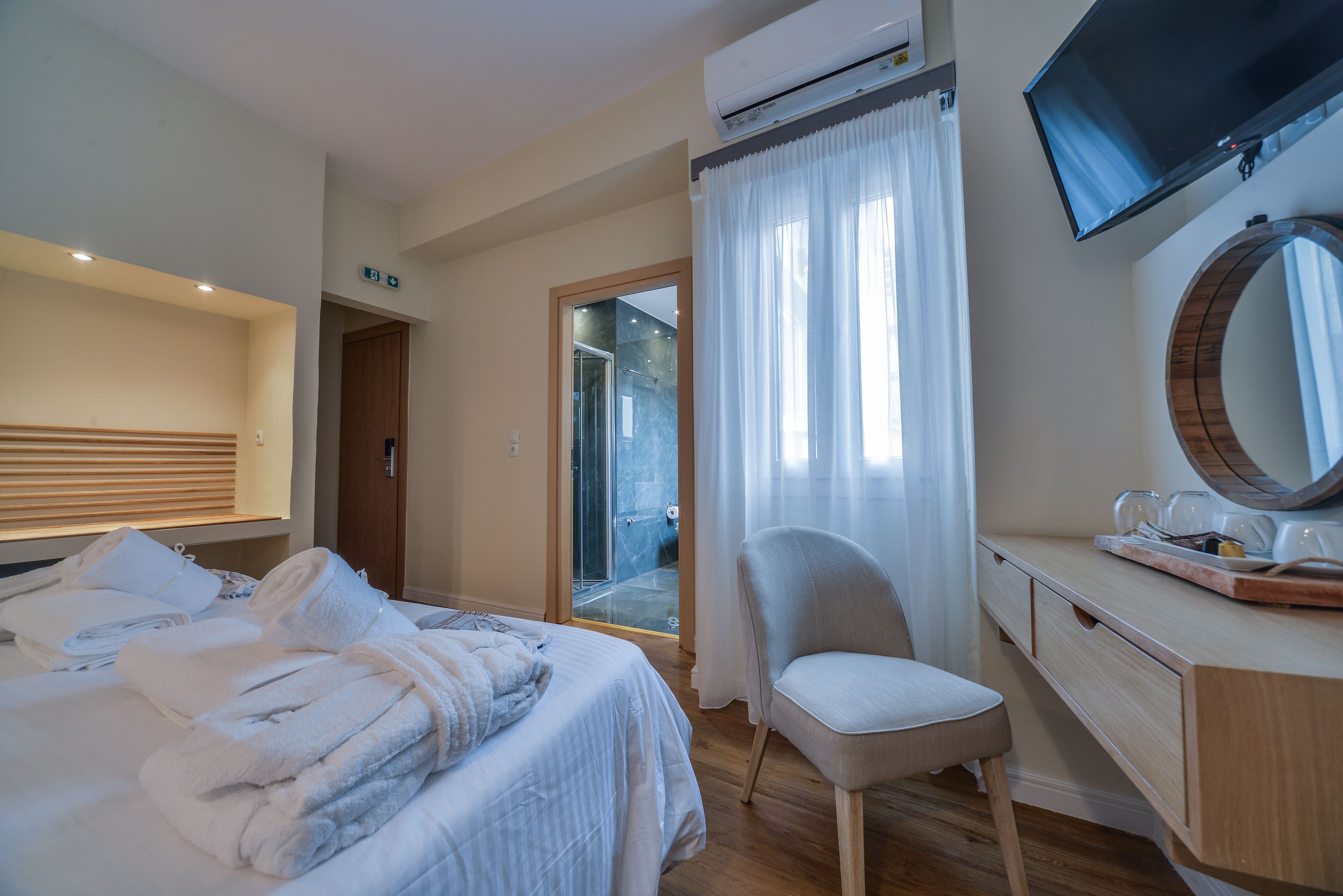 Une chambre d’hôtel comprenant un lit, un bureau avec un miroir, une chaise et un appareil de climatisation.