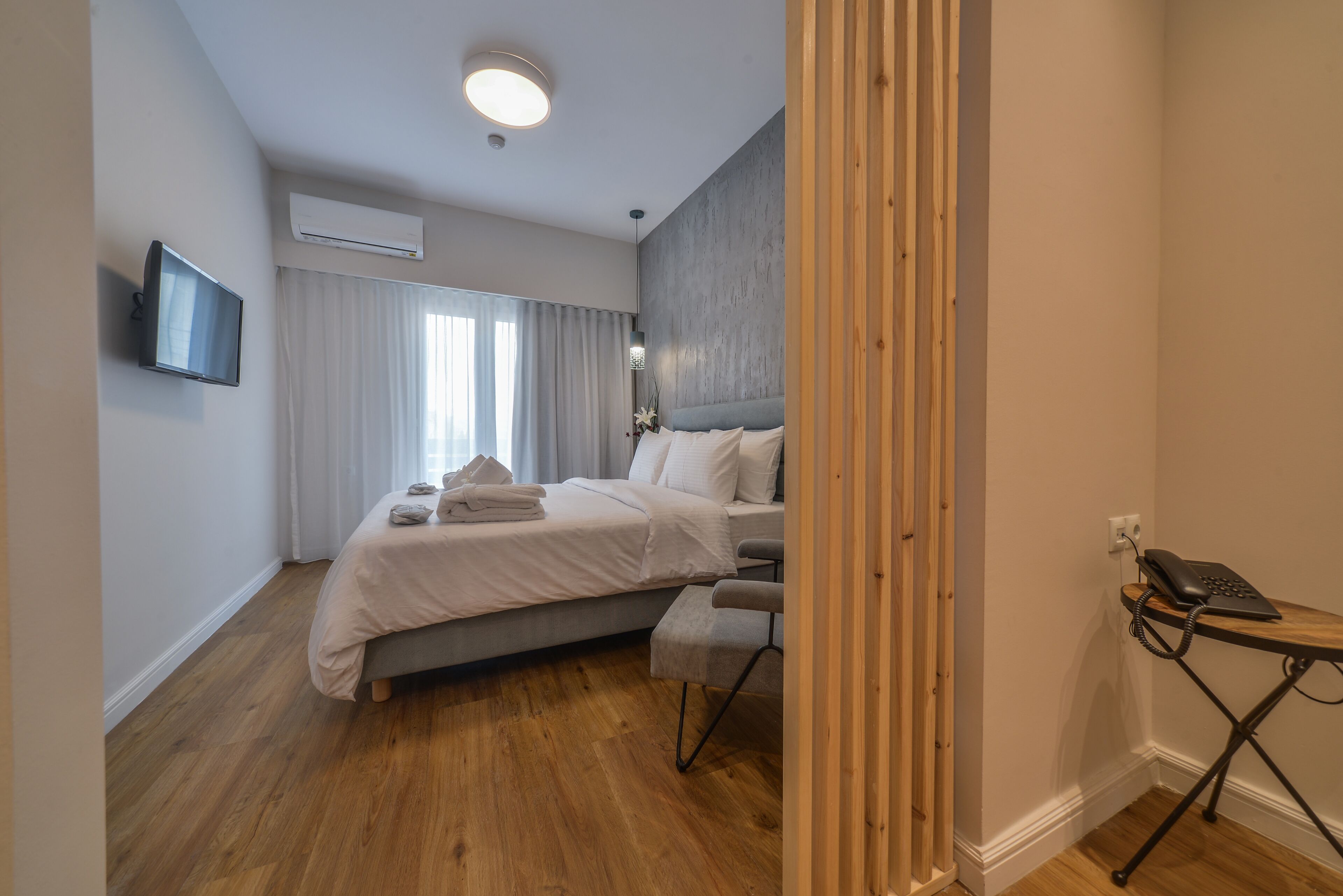 Ein modernes Hotelzimmer mit einem Bett, einem Schreibtisch, einem Sessel, einem Fernseher und einer Klimaanlage.