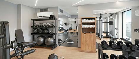 A modern gym with exercise equipment, kettlebells, and dumbbells.