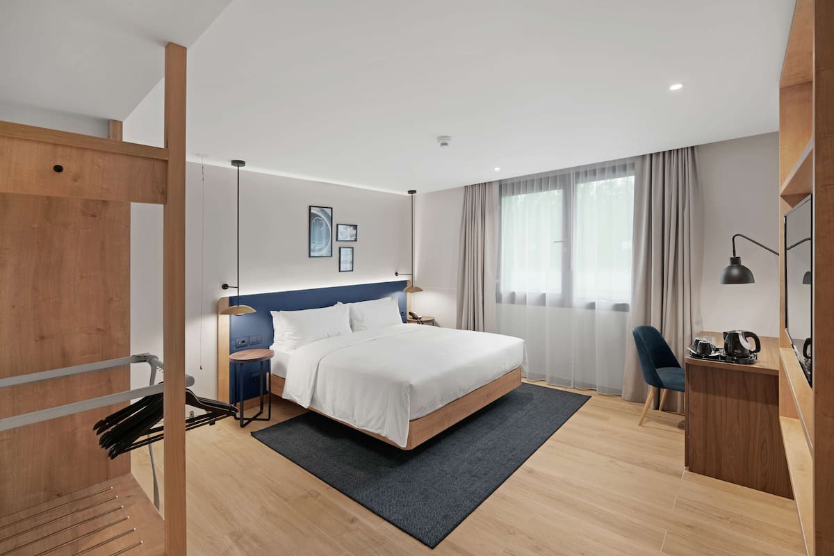 Una habitación de hotel moderna con una cama grande, un escritorio, una silla y un televisor.
