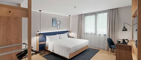 Una habitación de hotel moderna con una cama grande, un escritorio, una silla y un televisor.