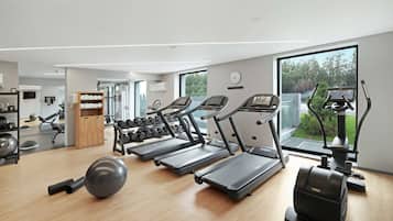 A modern gym with treadmills, a rowing machine, and free weights.