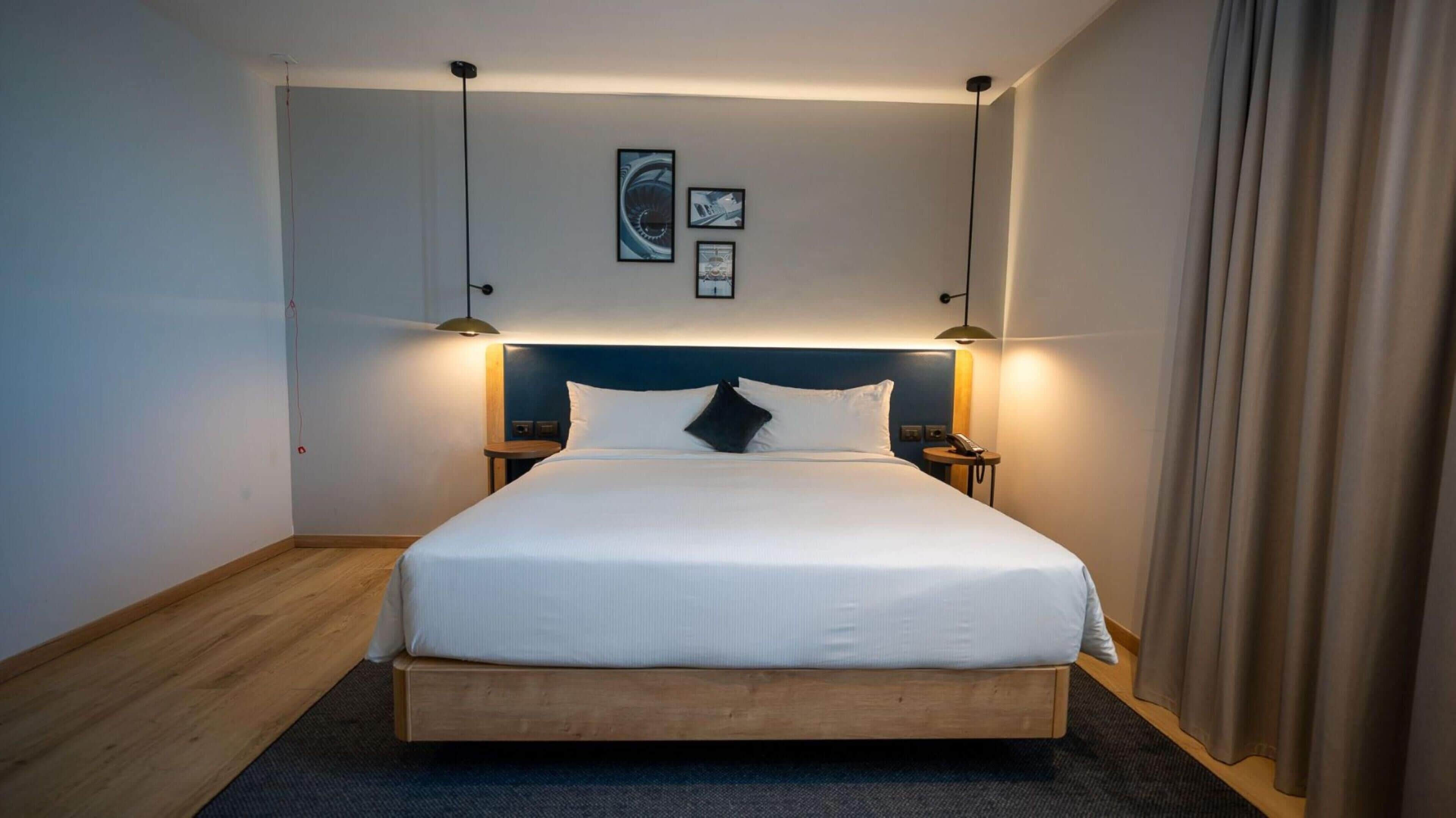 Een hotelkamer met een groot bed, twee nachtkastjes, een hoofdeinde en wanddecoratie.