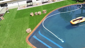 Une piscine à bordures courbes, entourée d’une bordure en briques et recouverte de carreaux bleus.