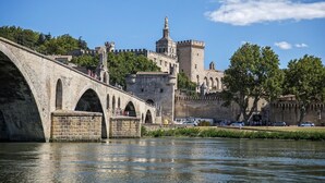 A stone bridge over a river with a castle in the background.