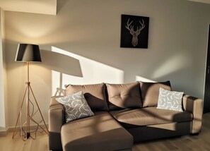 A modern living room with a sectional sofa, patterned throw pillows, a floor lamp, and a deer head artwork on the wall. - air-conditioned villa with heated pool just for you! (mirabel o baronnies)
