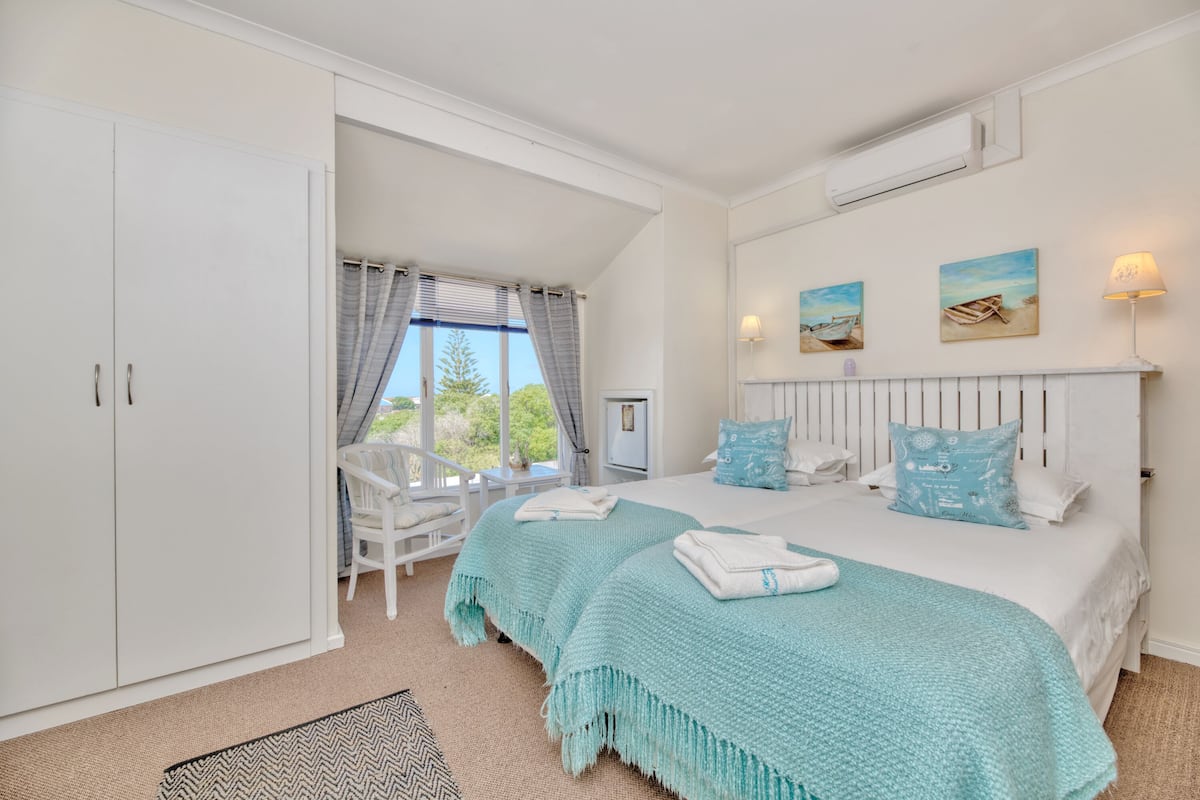A bedroom with a large bed, a wardrobe, a chair, and a window with curtains.