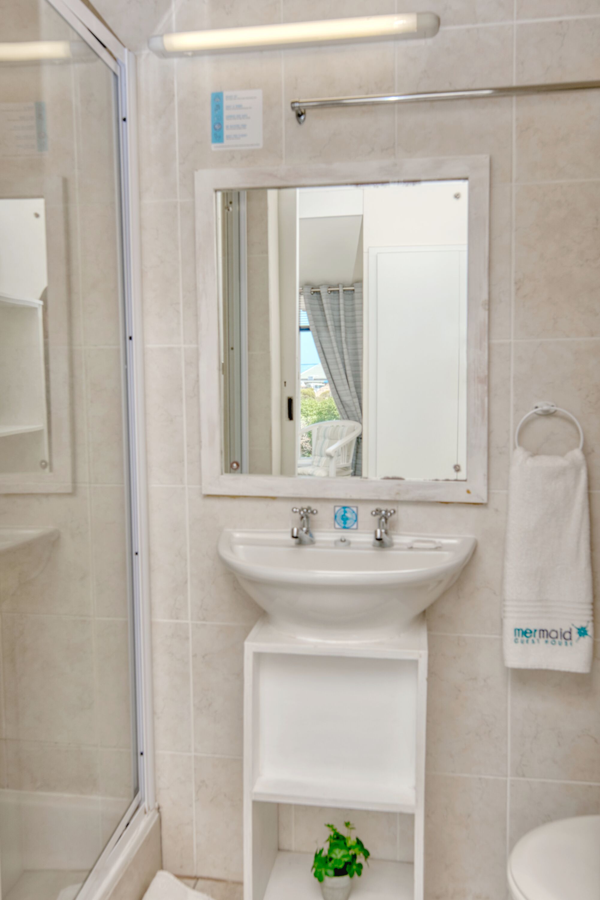 A bathroom with a white sink, a mirror, a towel rack, and a glass shower enclosure.