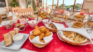 Ein reichhaltiges Frühstücksbuffet mit verschiedenen Speisen und einem schönen Ausblick durch die Fenster.
