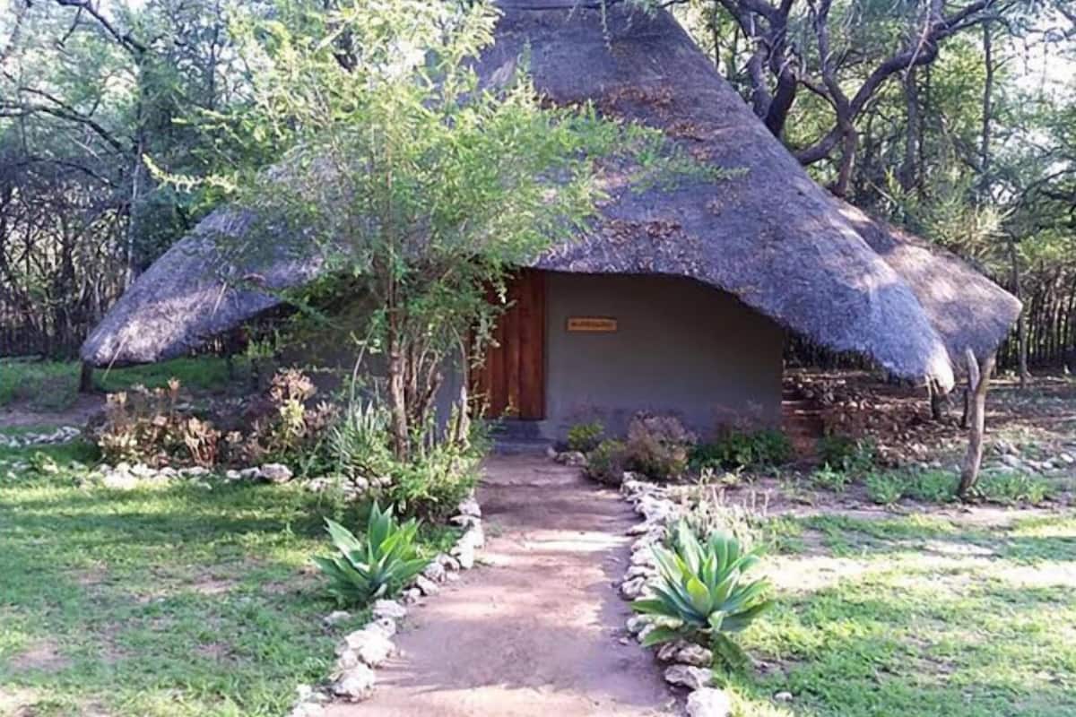 A thatched-roof hut with a wooden door and a sign above it.