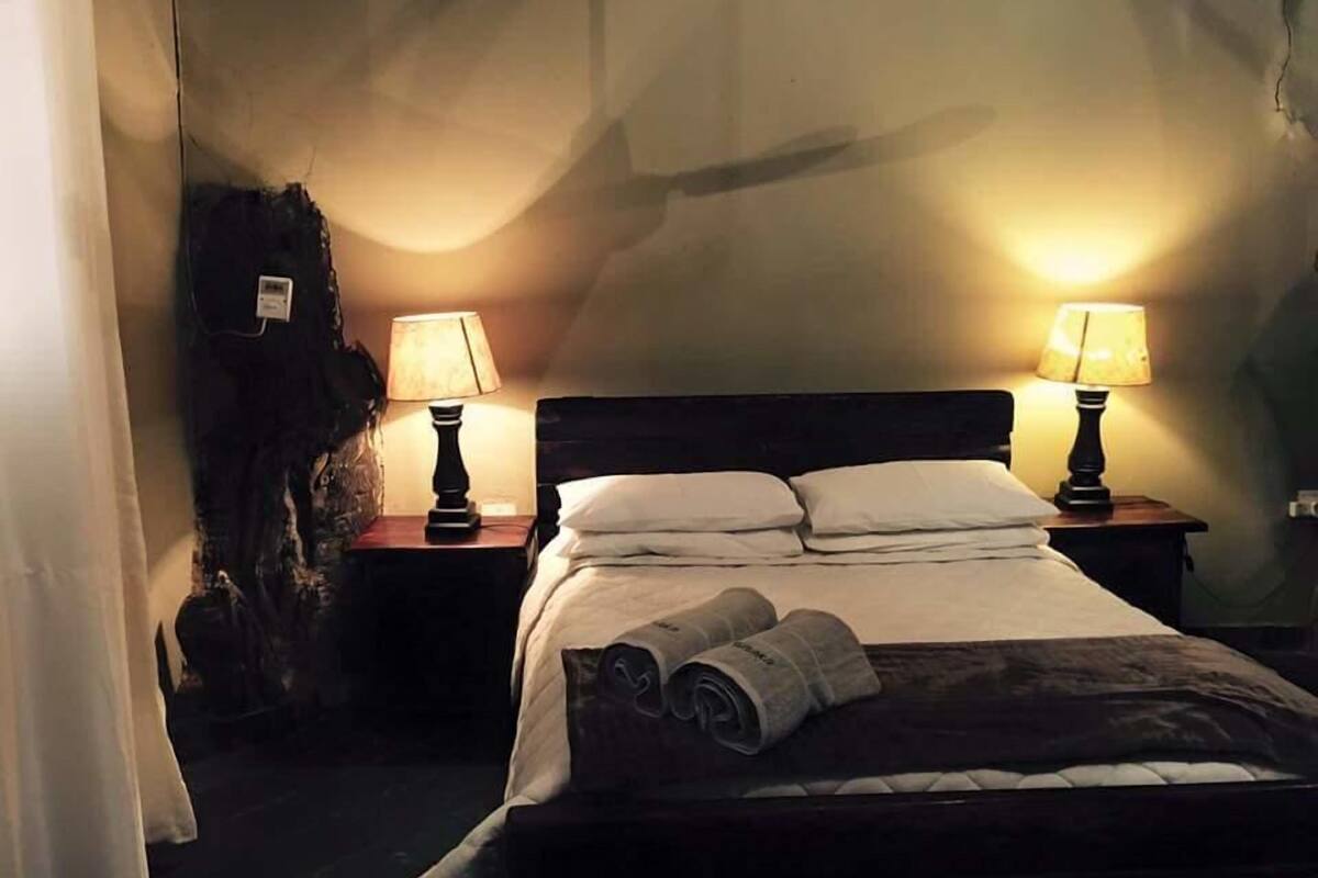 A hotel room with a bed, two bedside lamps, a nightstand, and a curtain.