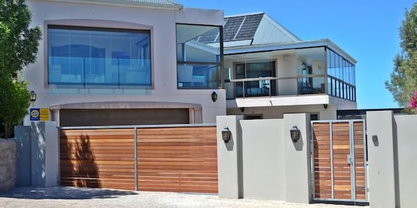 A modern two-story house with large windows, a garage, and a balcony.