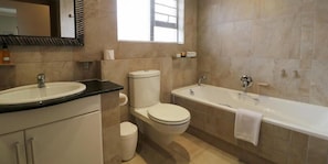 A modern bathroom with a sink, toilet, and bathtub.