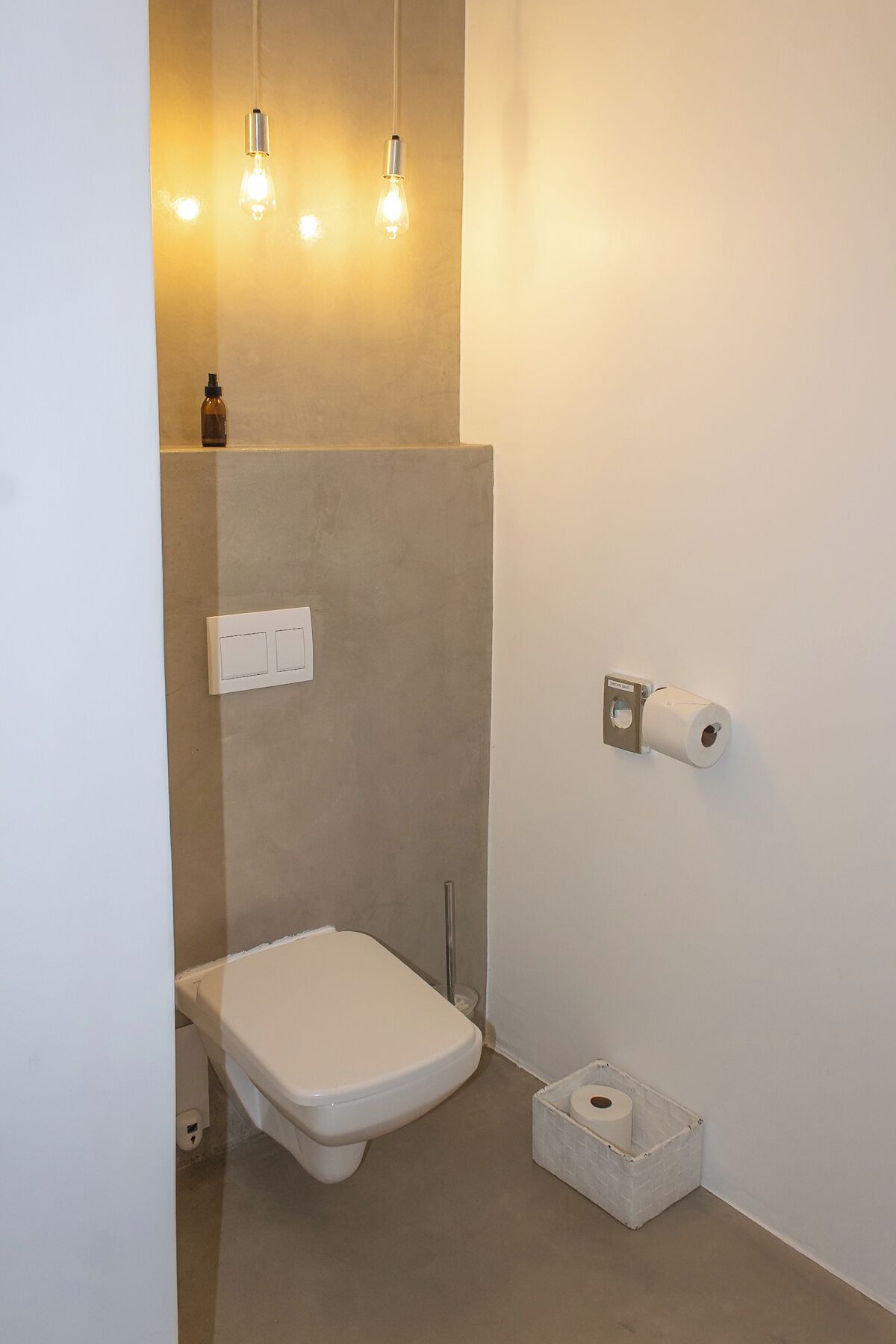 A small, modern bathroom with a toilet, a towel rack, and a toilet paper holder.