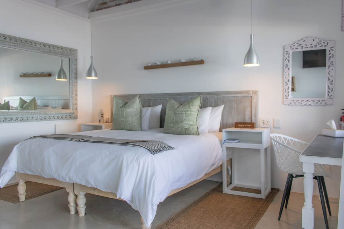 A neatly arranged bedroom with a large bed, bedside tables, a chair, and a desk.