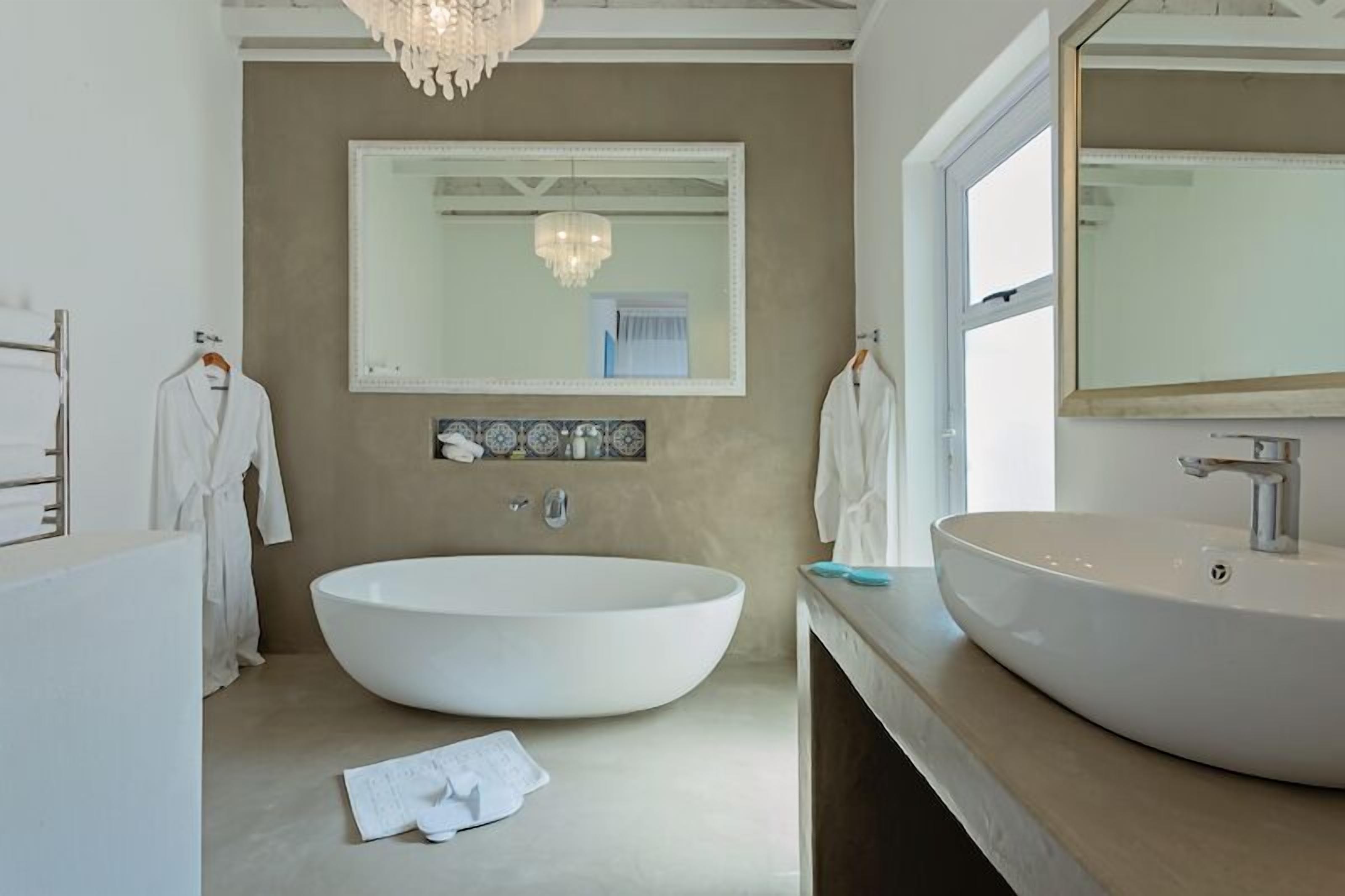 A modern bathroom with a large freestanding bathtub, a round sink, and a large mirror above the sink.