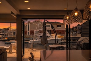 A marina with boats docked, a house in the background, and a dining area with outdoor seating. - 4536 Costa De Oro - Waterfront Wonderland (Oxnard)
