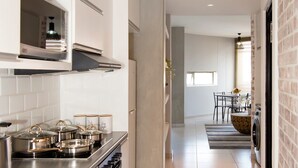 A modern kitchen with white cabinets, stainless steel appliances, and a central island with a sink. - Wild Olive 11 (Windhoek)