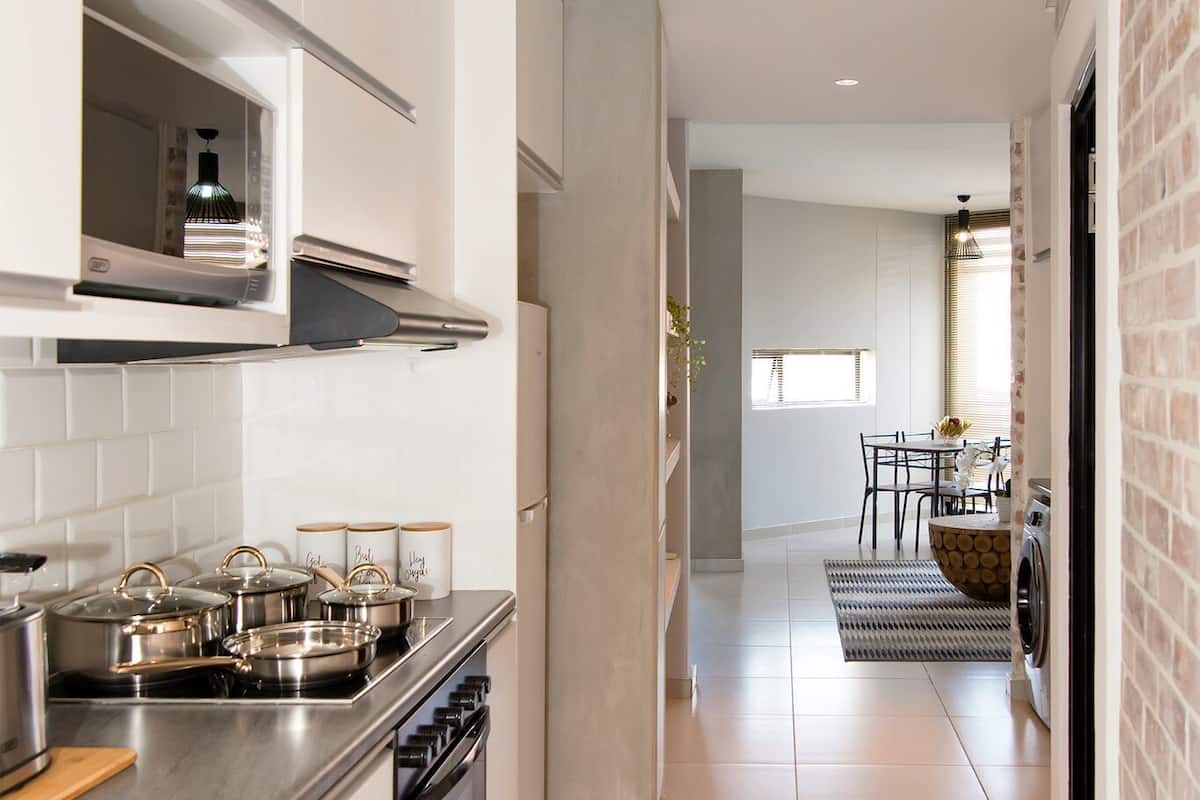 A modern kitchen with white cabinets, stainless steel appliances, and a central island with a sink.