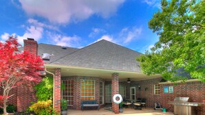 Een huis met een zwembad, een overdekt terras en een barbecueplek.