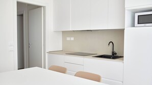 Une cuisine moderne avec des armoires blanches, un robinet noir et un four à micro-ondes posé sur le plan de travail.