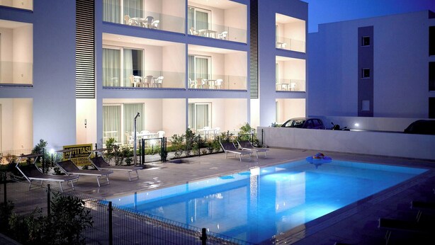 Un hôtel moderne dot é d’une piscine, de nombreux balcons et d’espaces extérieurs aménagés pour se détendre.