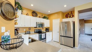 A modern kitchen with white cabinets, stainless steel appliances, and decorative items on the walls.
