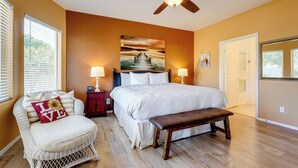 A bedroom with a bed, a bench, a chair, a nightstand, and a ceiling fan.