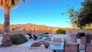 A backyard with a pool, seating area, and a view of mountains.