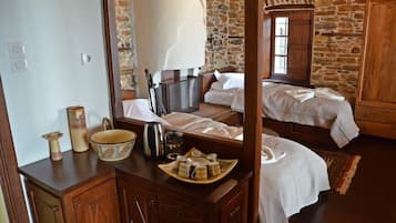 A rustic bedroom with a stone wall, wooden furniture, and a bed with white linens.