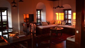 A cozy living room with a sofa, a coffee table, and a TV. There are bookshelves and a dining table with chairs. - Fyloma (South Pelion)