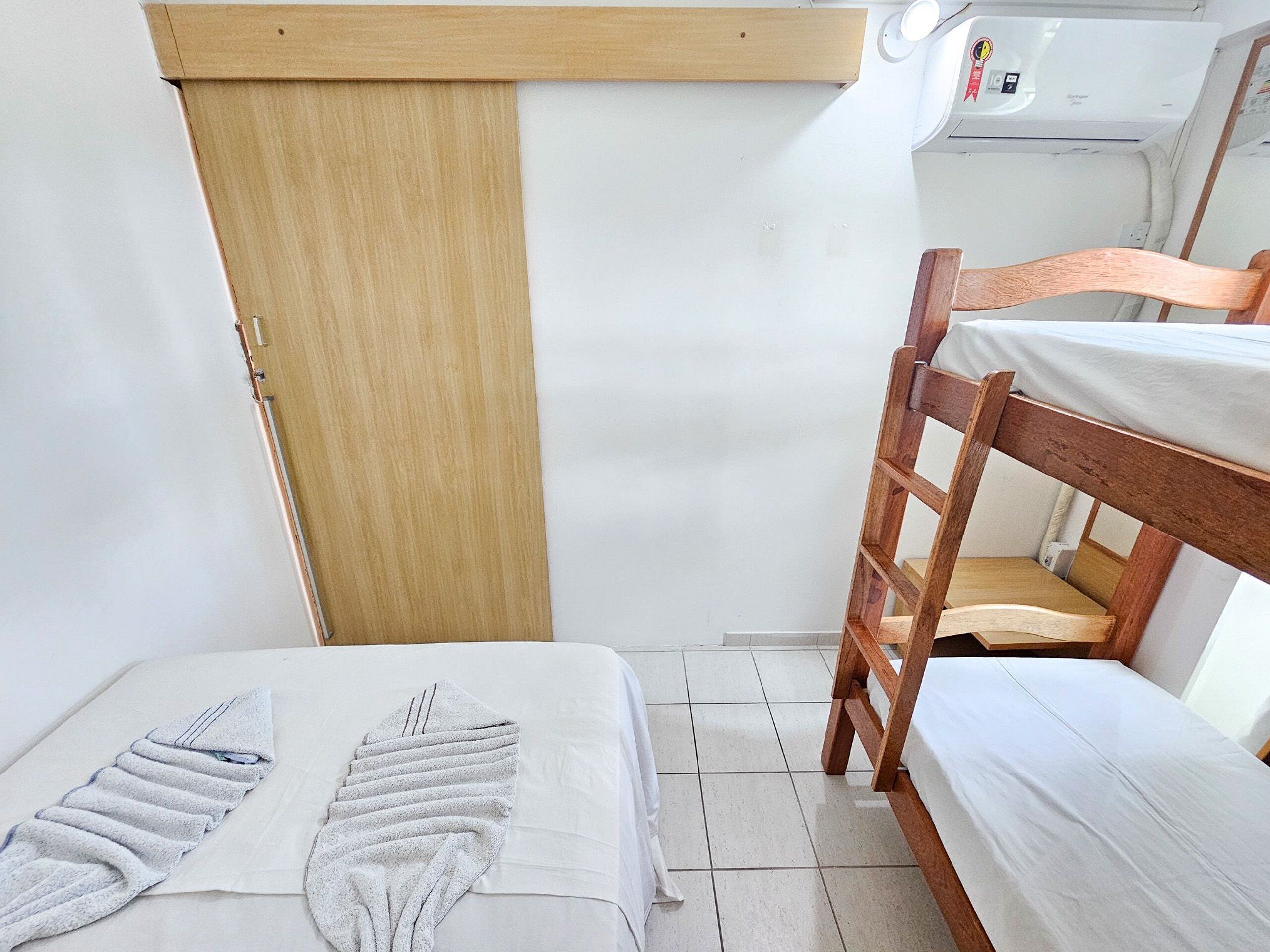 A bunk bed room with a wooden ladder, a bed with a white sheet, and a towel.