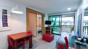 A modern living room with a dining area, a TV, and a balcony with a view. - Flats no Beach Class de Muro Alto (Ipojuca)