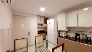 A compact kitchen with a refrigerator, microwave, and coffee maker. - Flats no Beach Class de Muro Alto (Ipojuca)