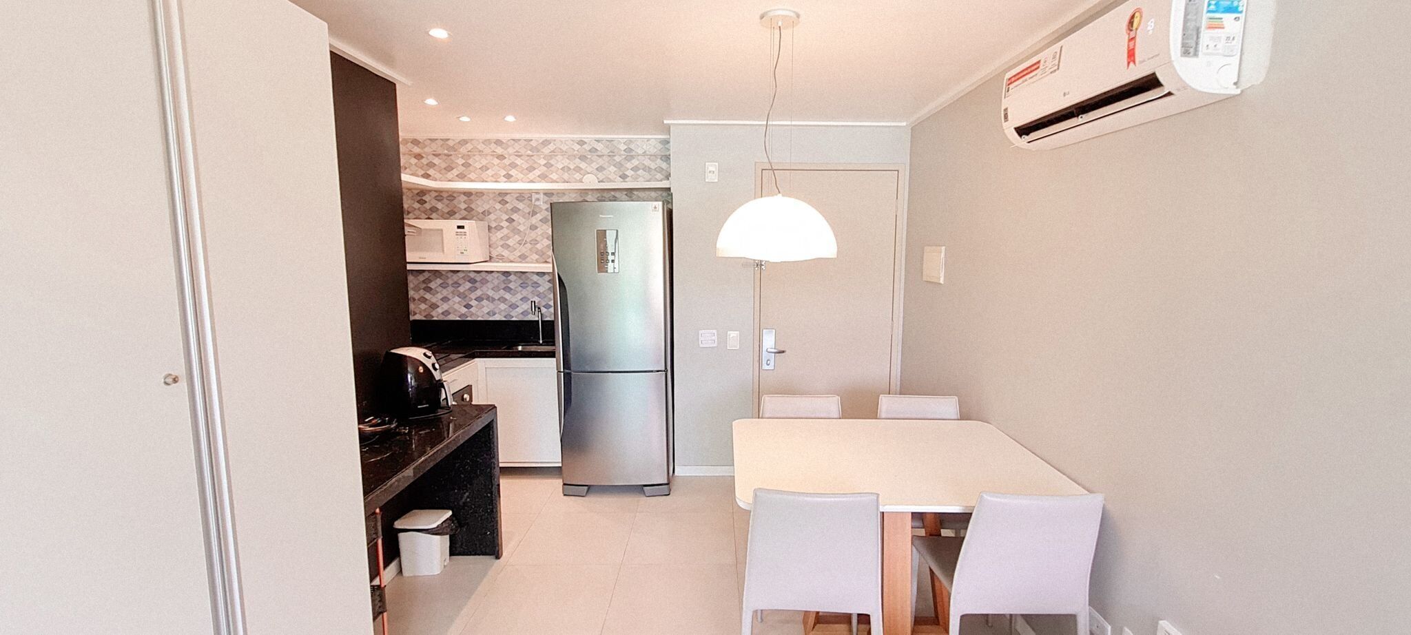 A compact kitchen with a refrigerator, microwave, and a dining area with chairs and a table.