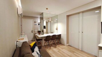 A compact living space with a dining area, a sofa, a mirror, and a wardrobe.