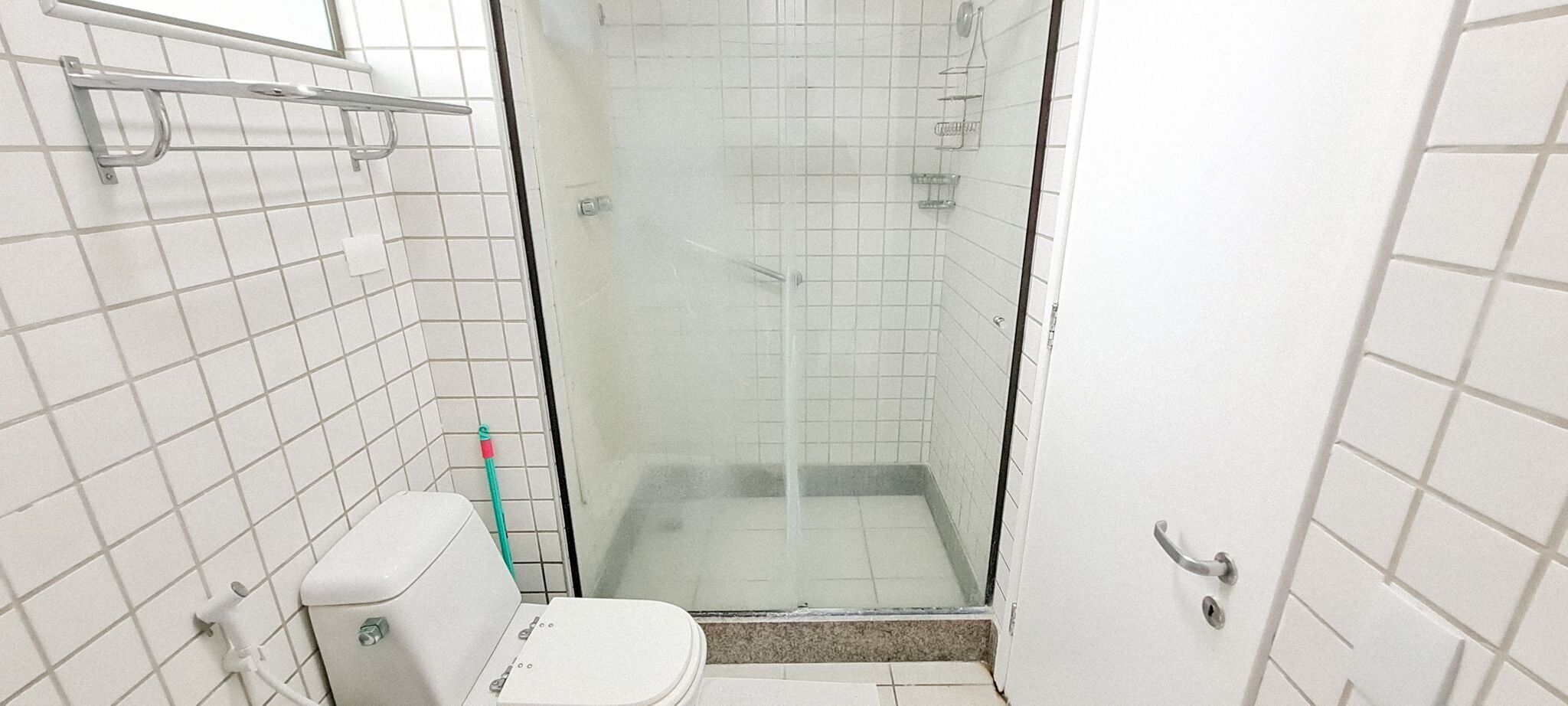 A small, tiled bathroom with a toilet, a shower stall, and a glass door.